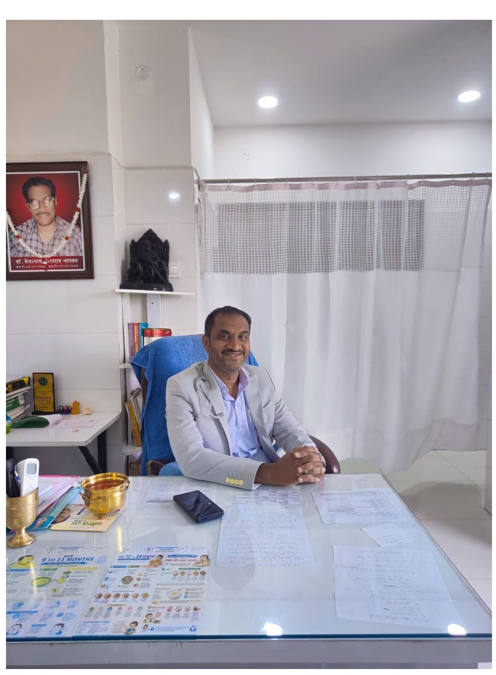 A doctor consulting with a patient across a desk in the consultation room at Bhagwat Hospital